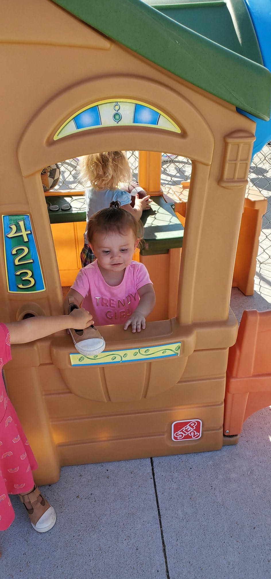 Child in a pink shirt playing in a toy house
