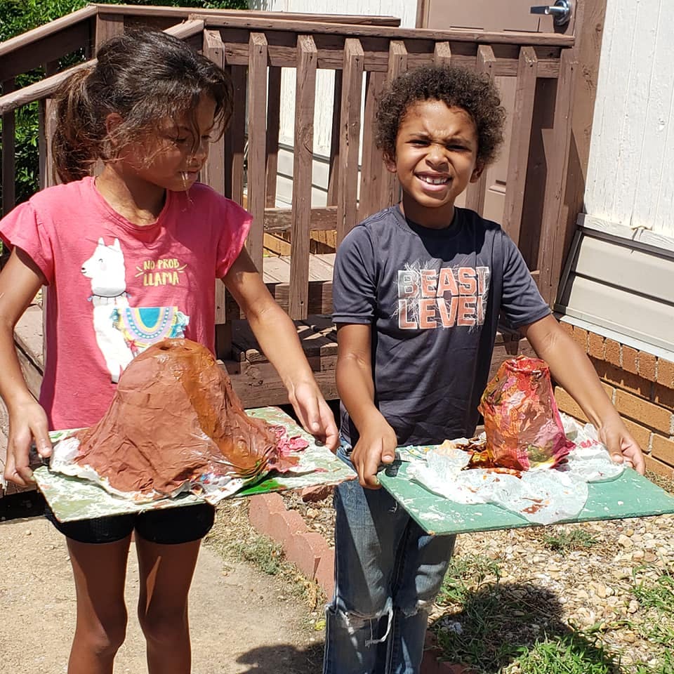 Two children holding erupting volcano science projects
