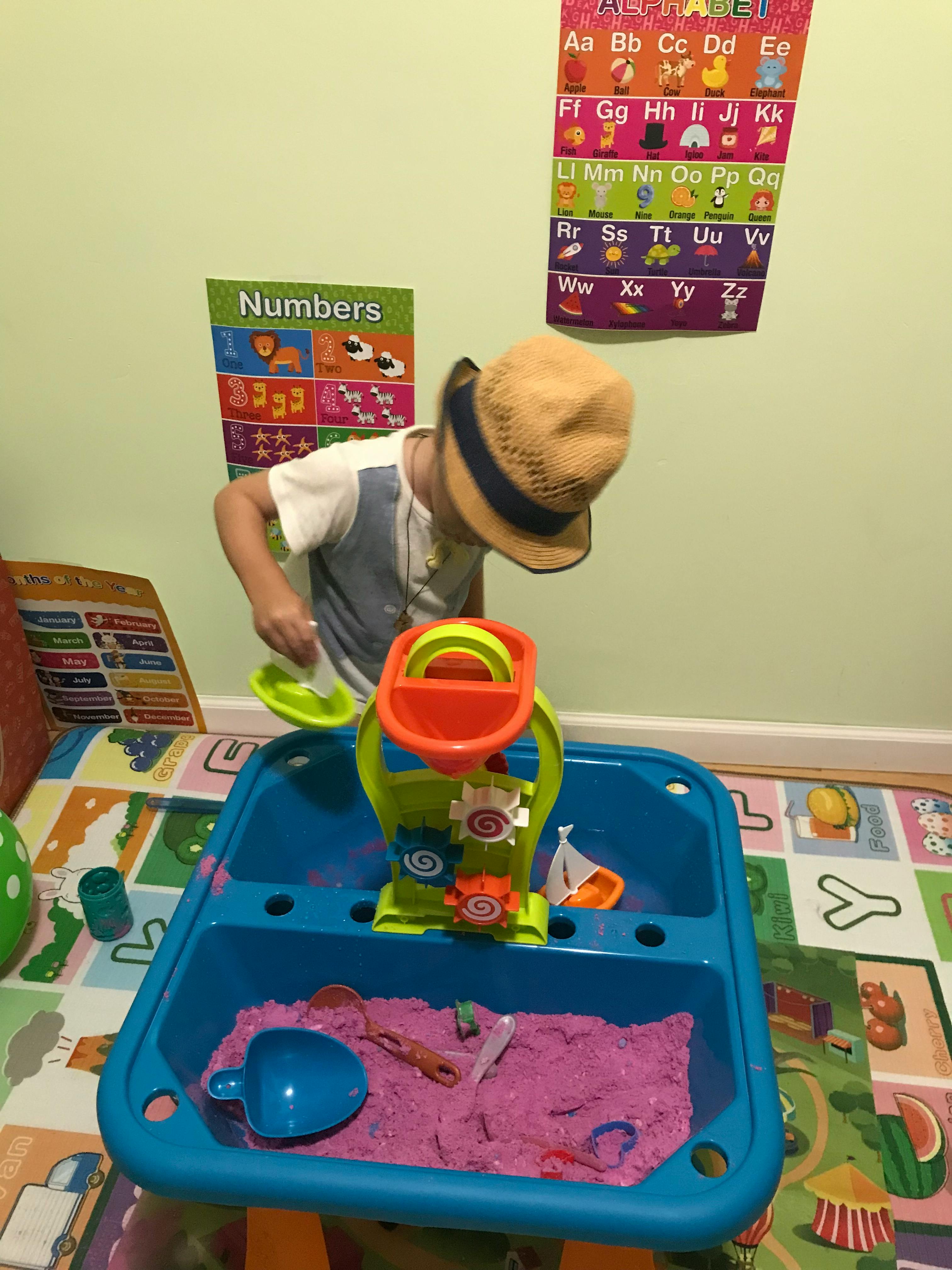 Child in a hat playing with a sand and water table