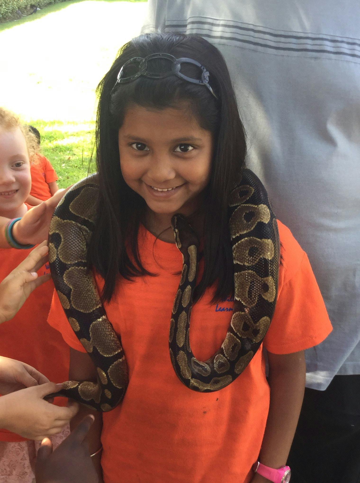 Child with a snake draped around their neck