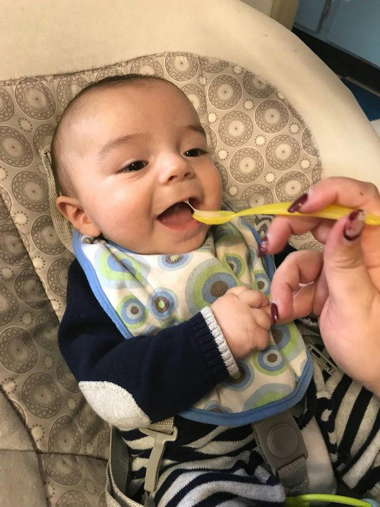 Child in a high chair being fed with a yellow spoon
