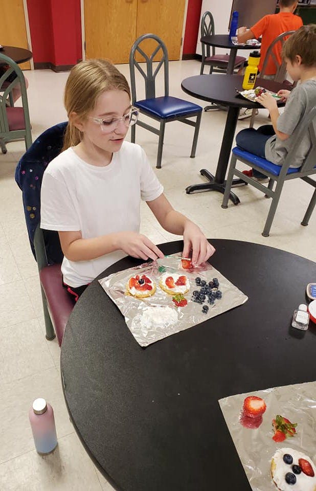 Child making fruit tarts at a table