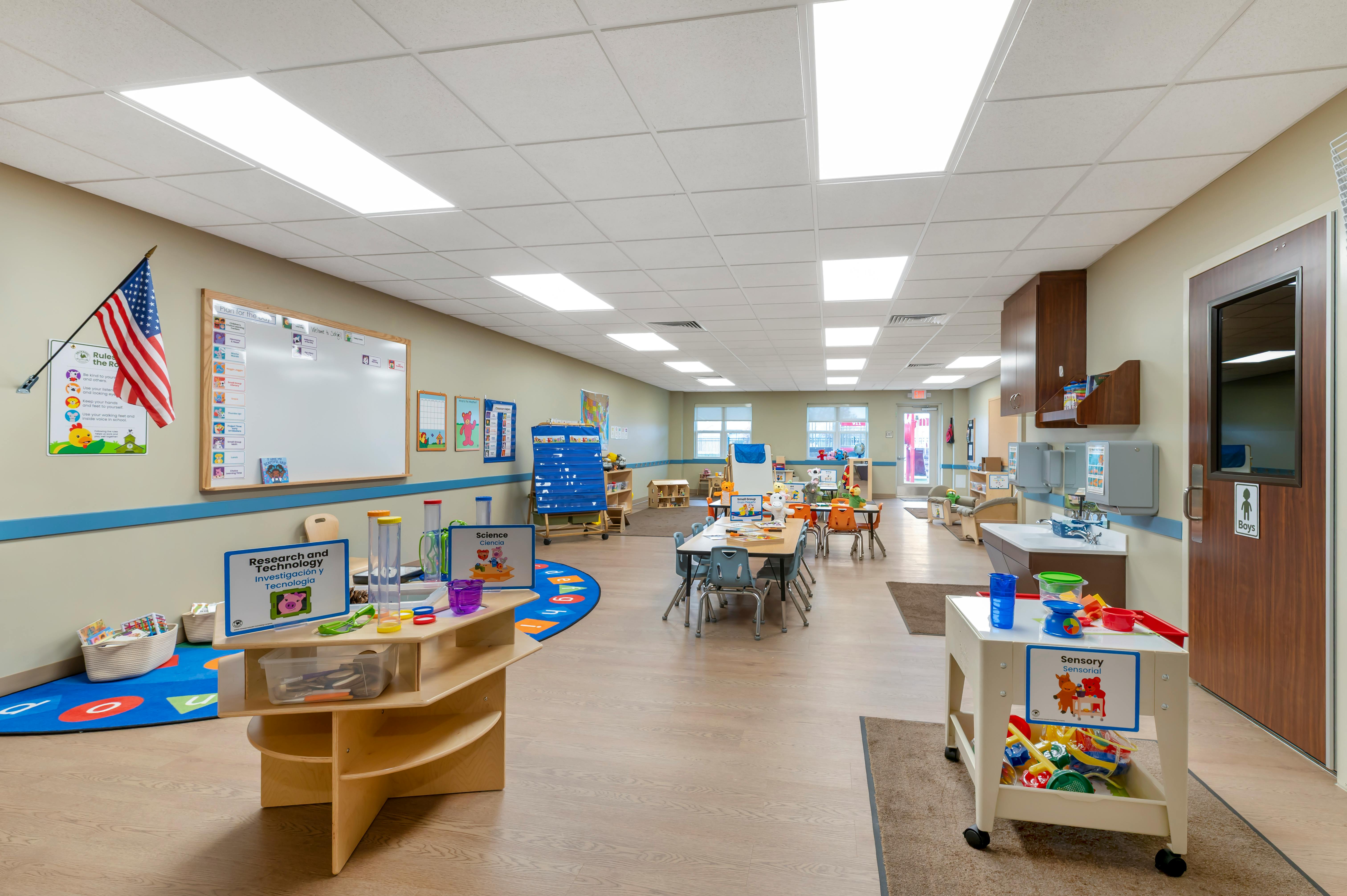 Classroom with tables, chairs, a whiteboard, and various learning stations