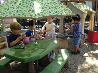 Children playing at a small picnic table under an umbrella
