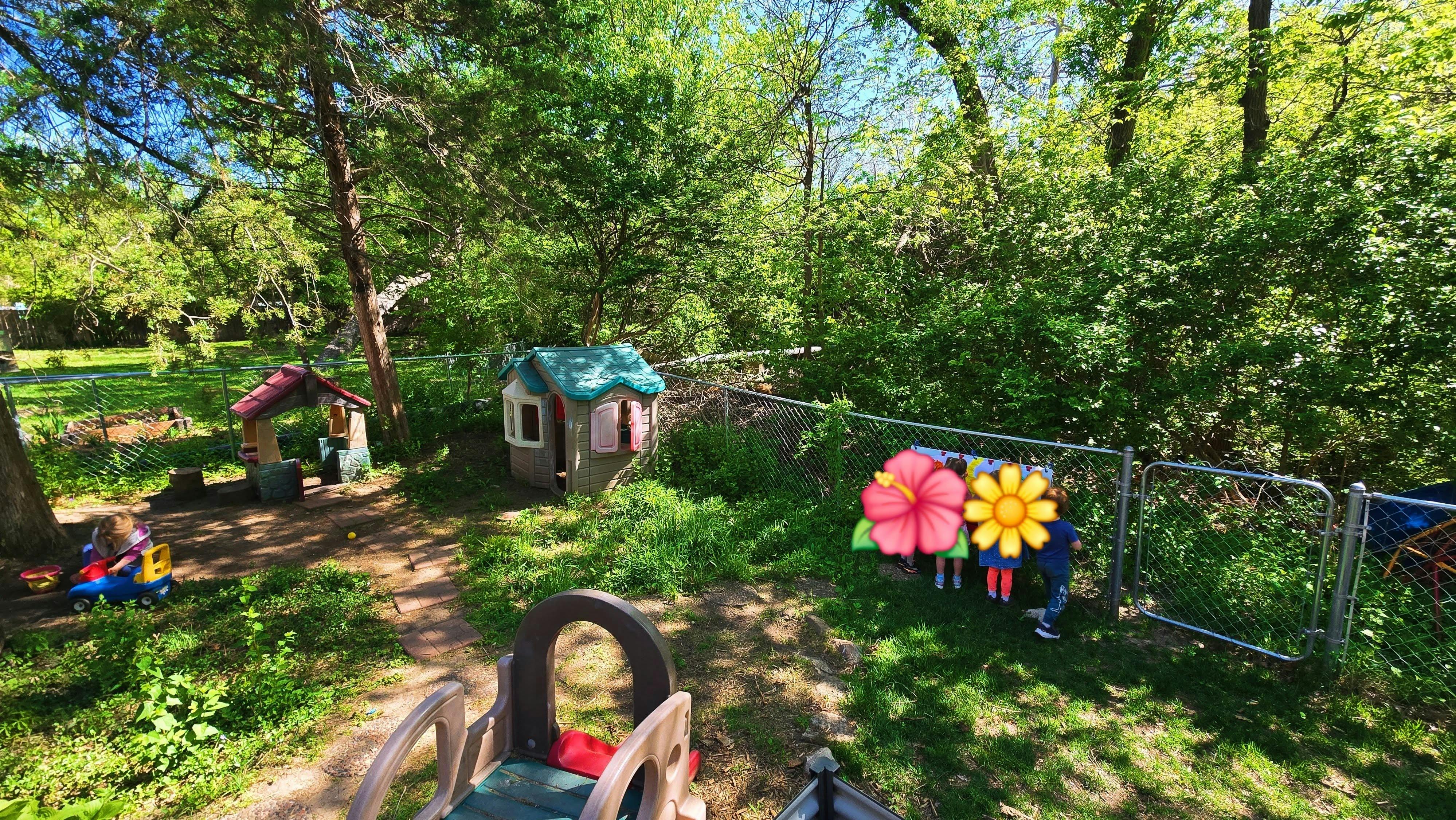 Children playing with toys in a wooded backyard with a playhouse