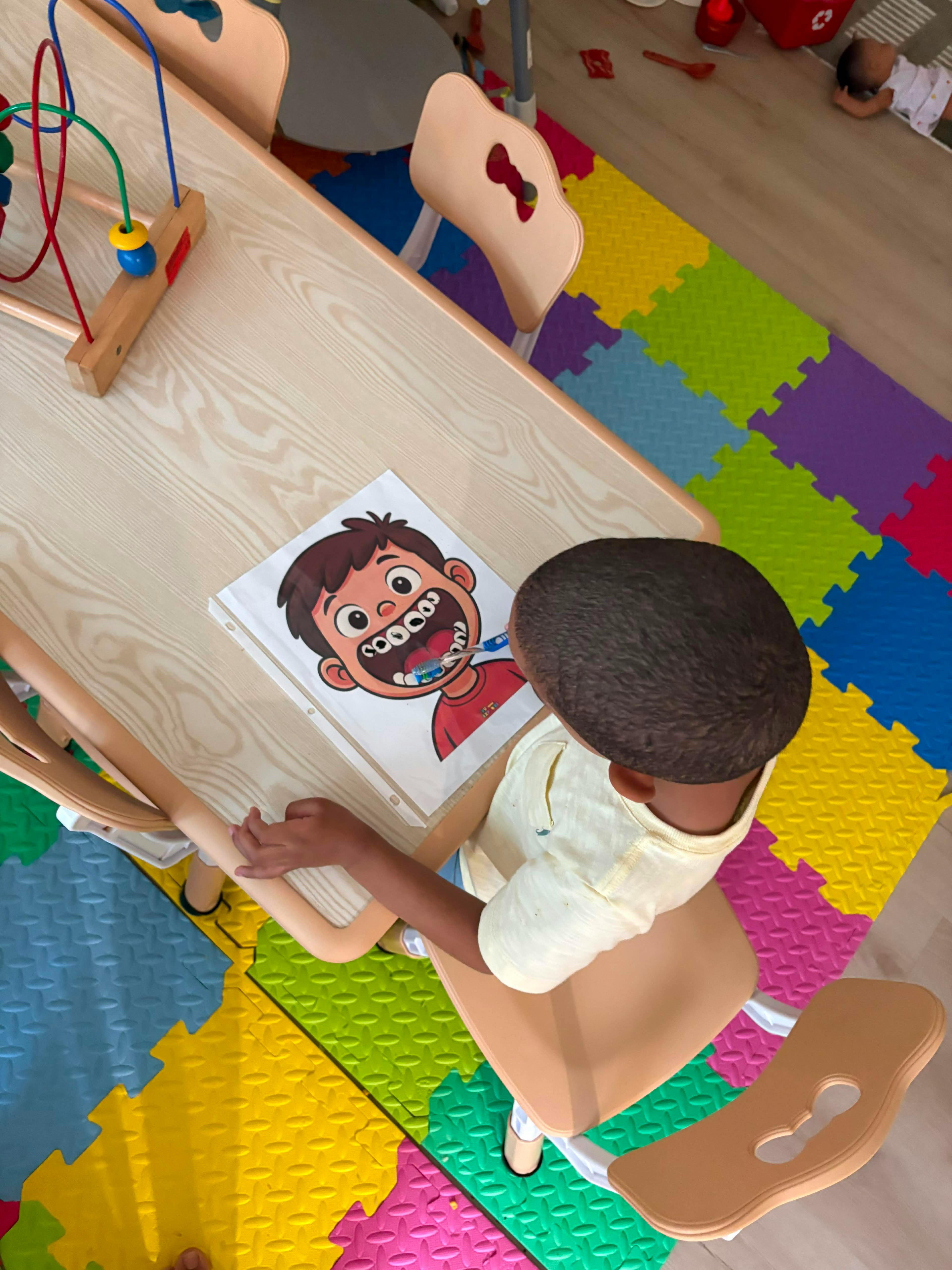 Child practicing brushing teeth on a cartoon diagram