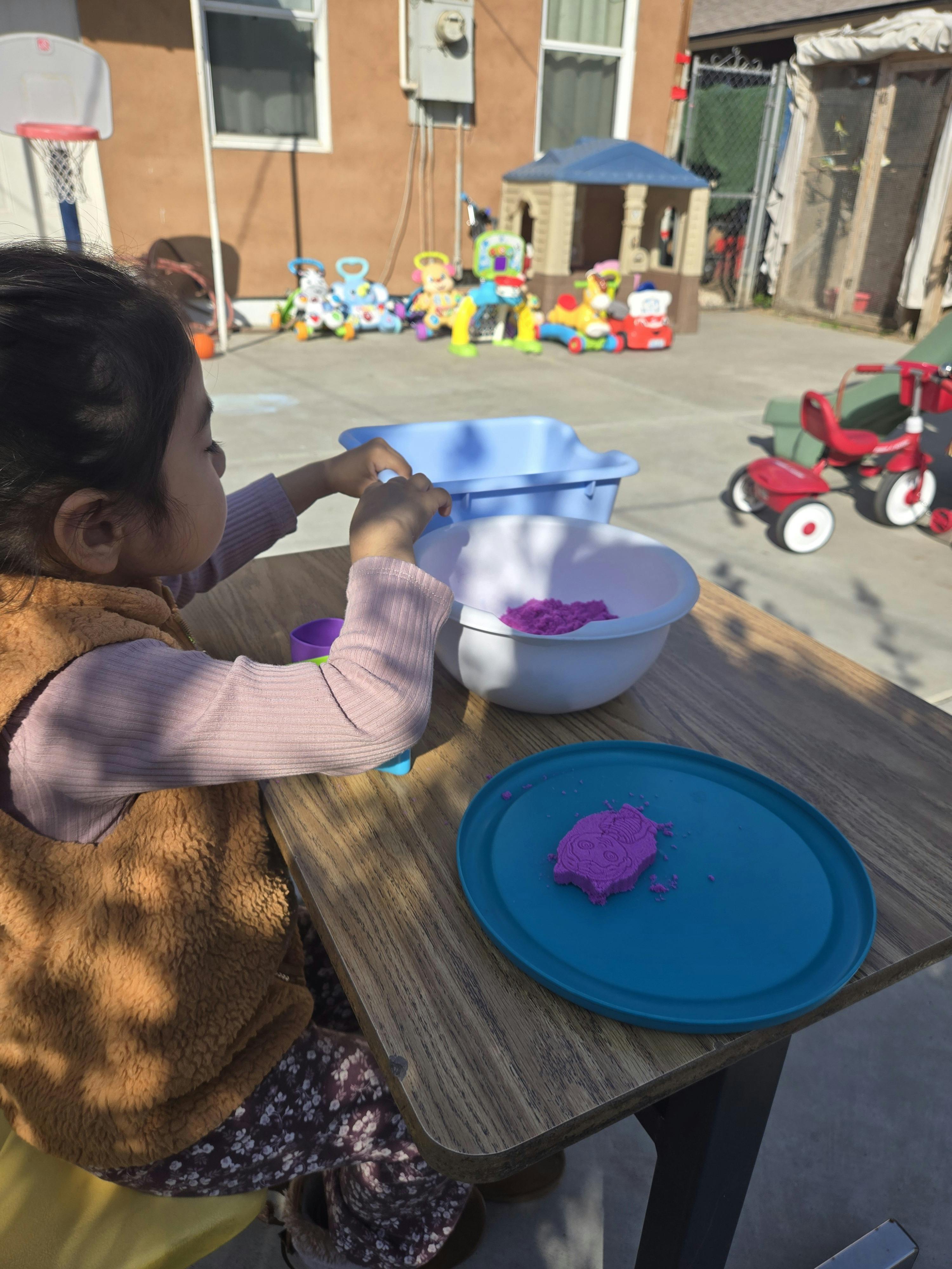 Child playing with kinetic sand at a table outdoors