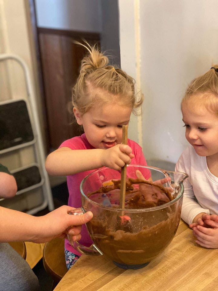 Child stirring a bowl of batter with another child watching