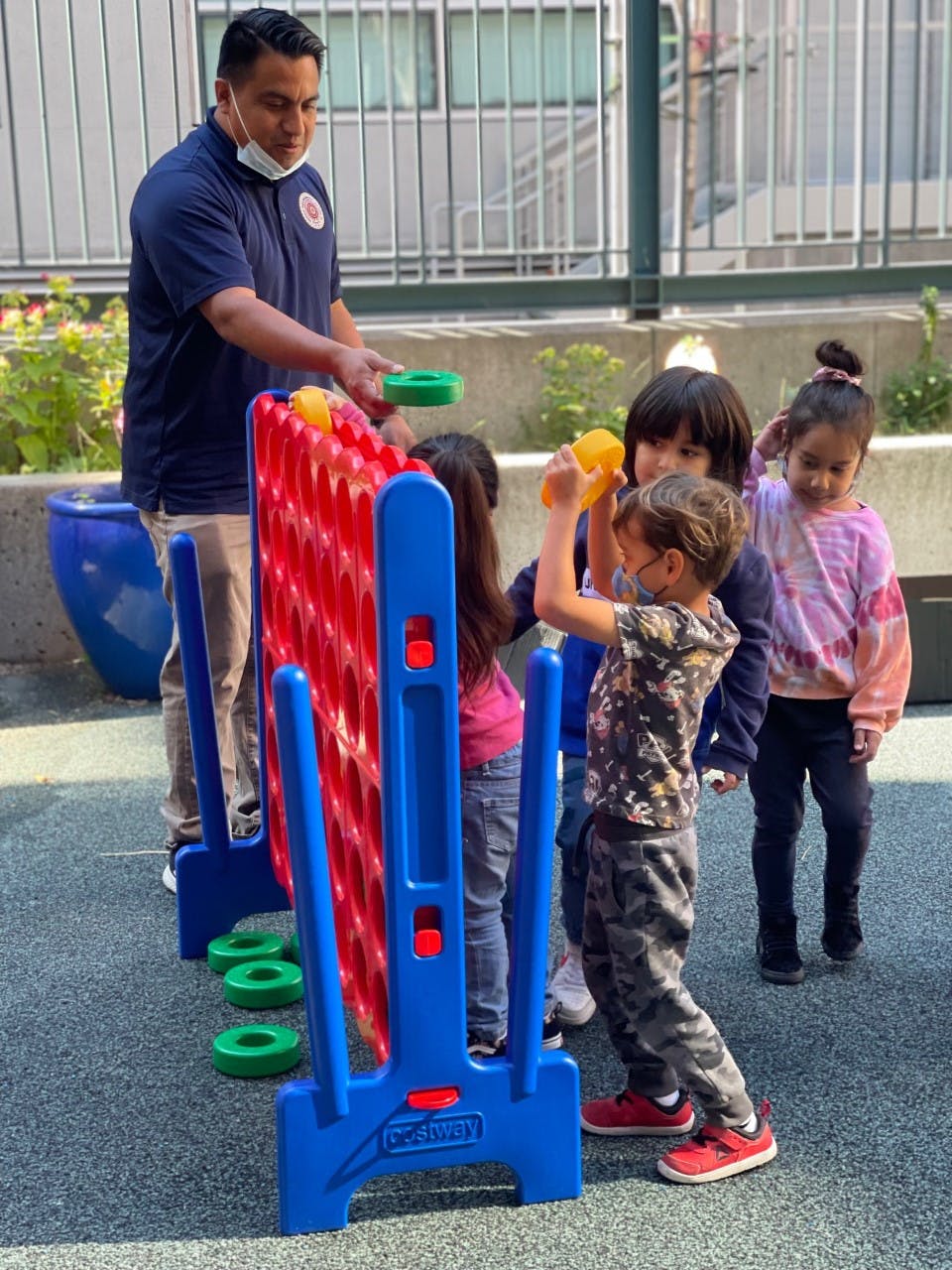 Person and children playing a large connect four game outdoors