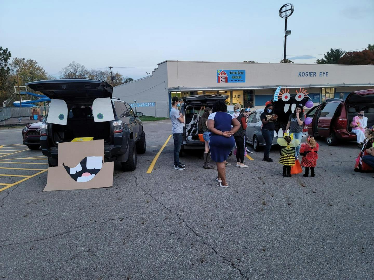 People and children in costumes gathered around cars with open trunks