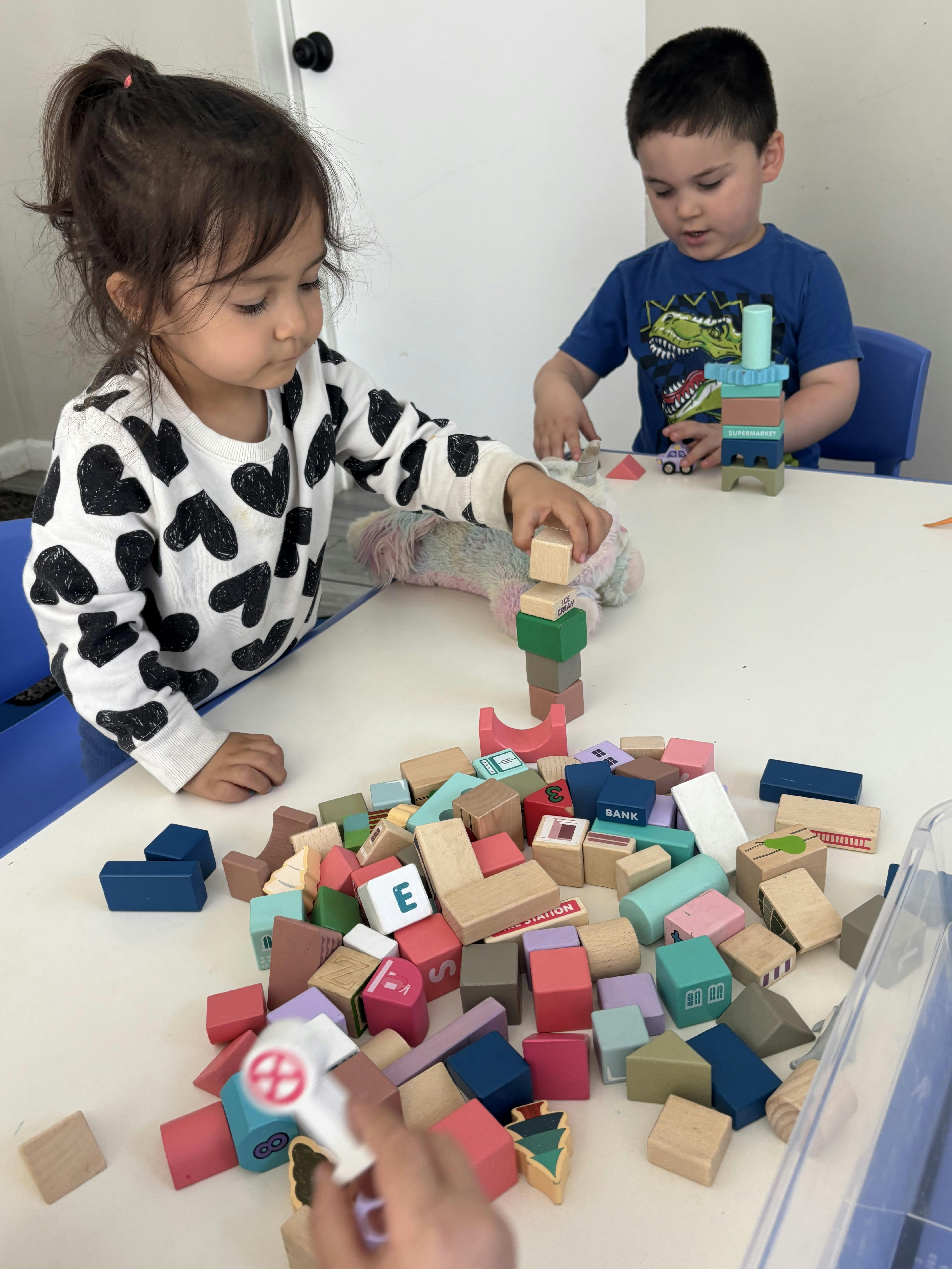 Two children playing with building blocks at a table