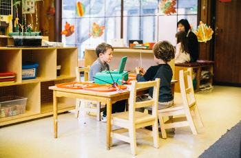 Two children sitting at a table in a classroom