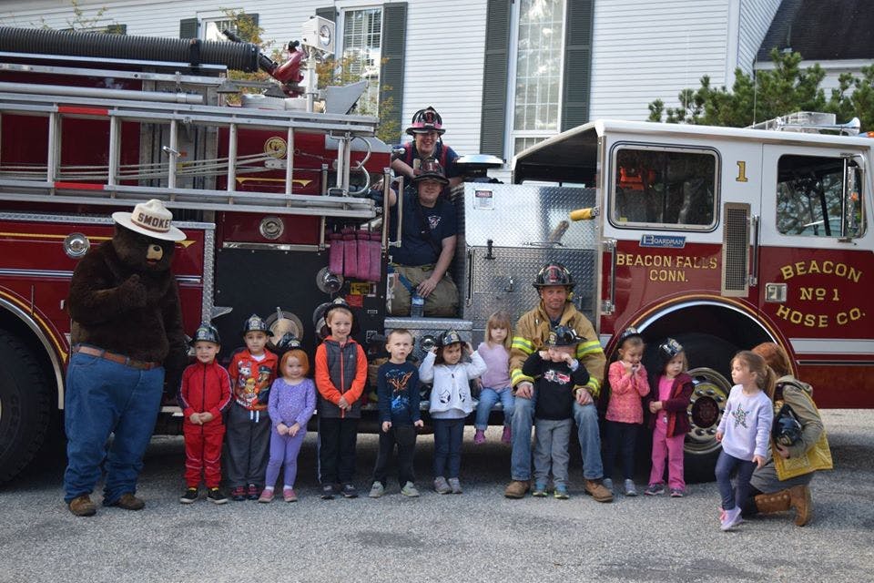 Smokey Bear, firefighters, and children posing in front of a fire truck
