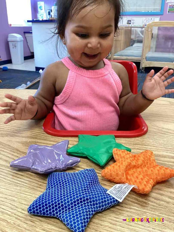 Child in a high chair with star-shaped toys on a table