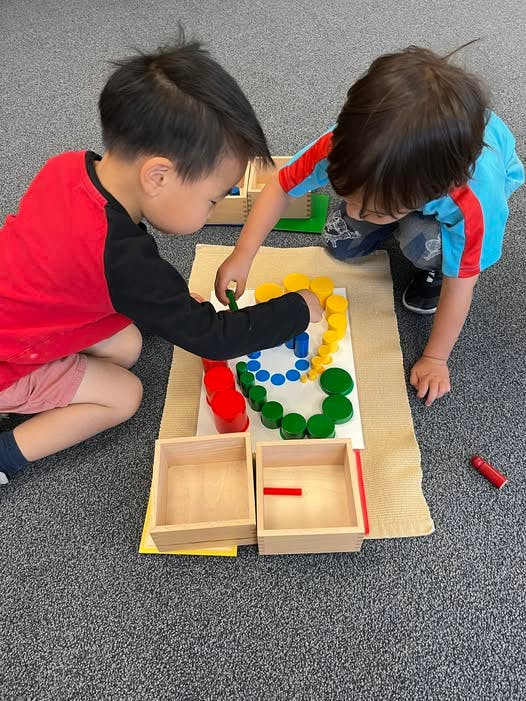 Two children playing with colorful shapes on the floor