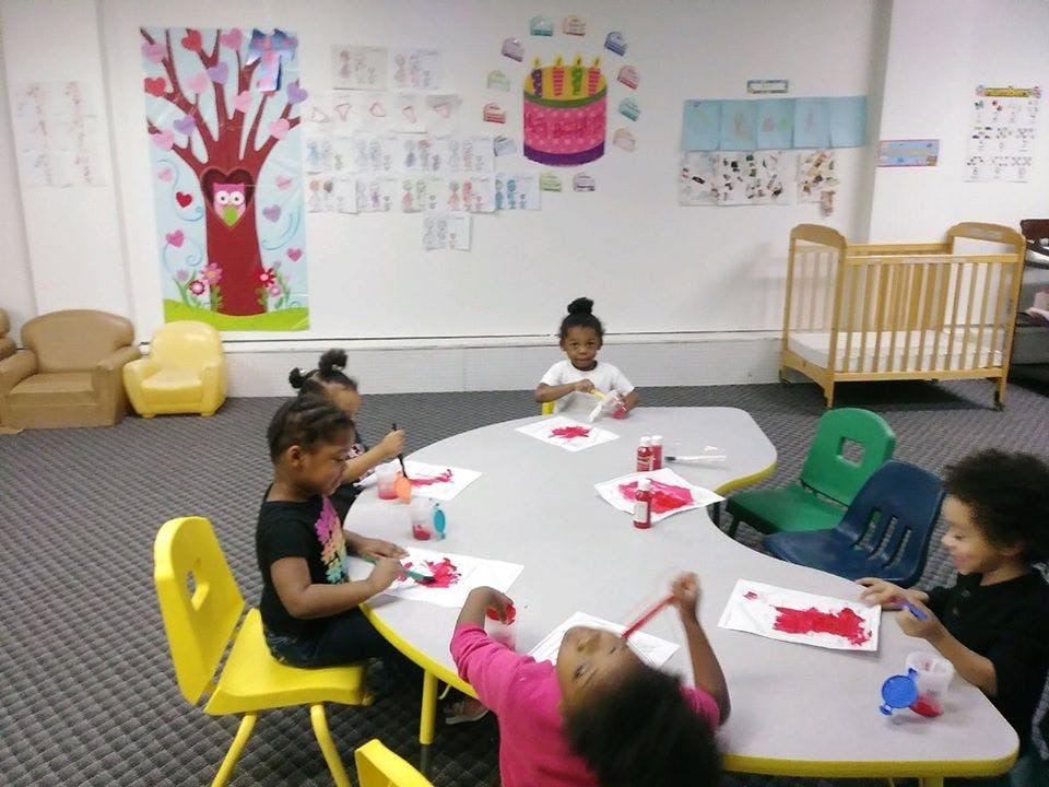 Children painting at a table in a classroom