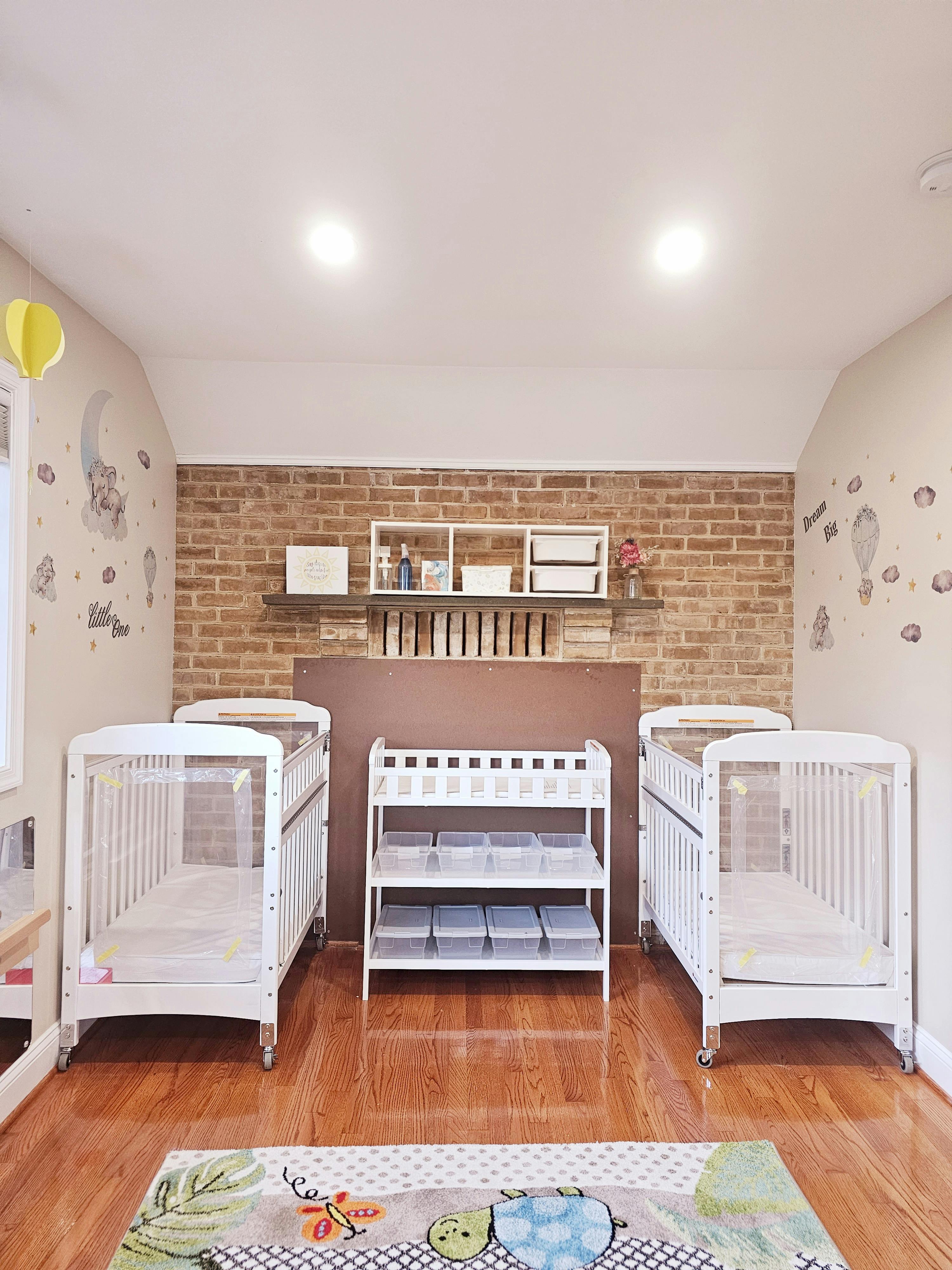 Two white cribs with a changing table and storage shelves in a room
