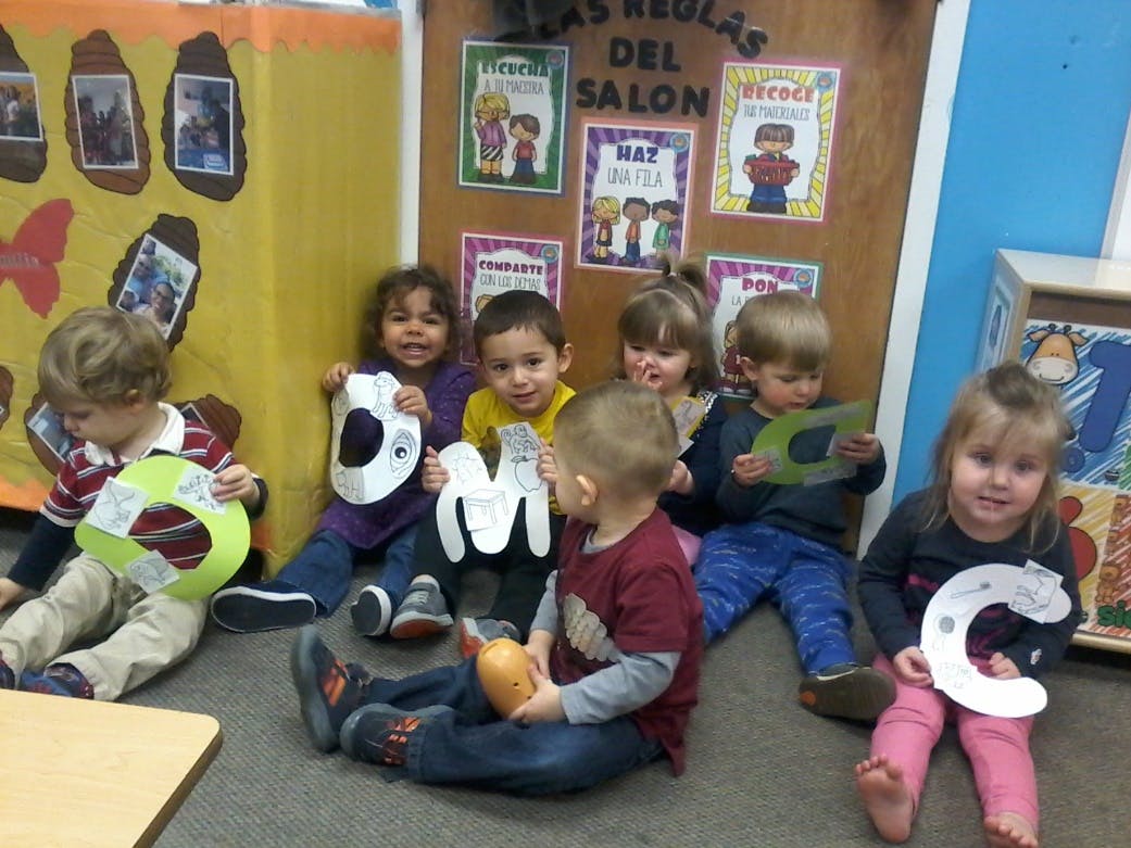 Children sitting on the floor holding paper letters