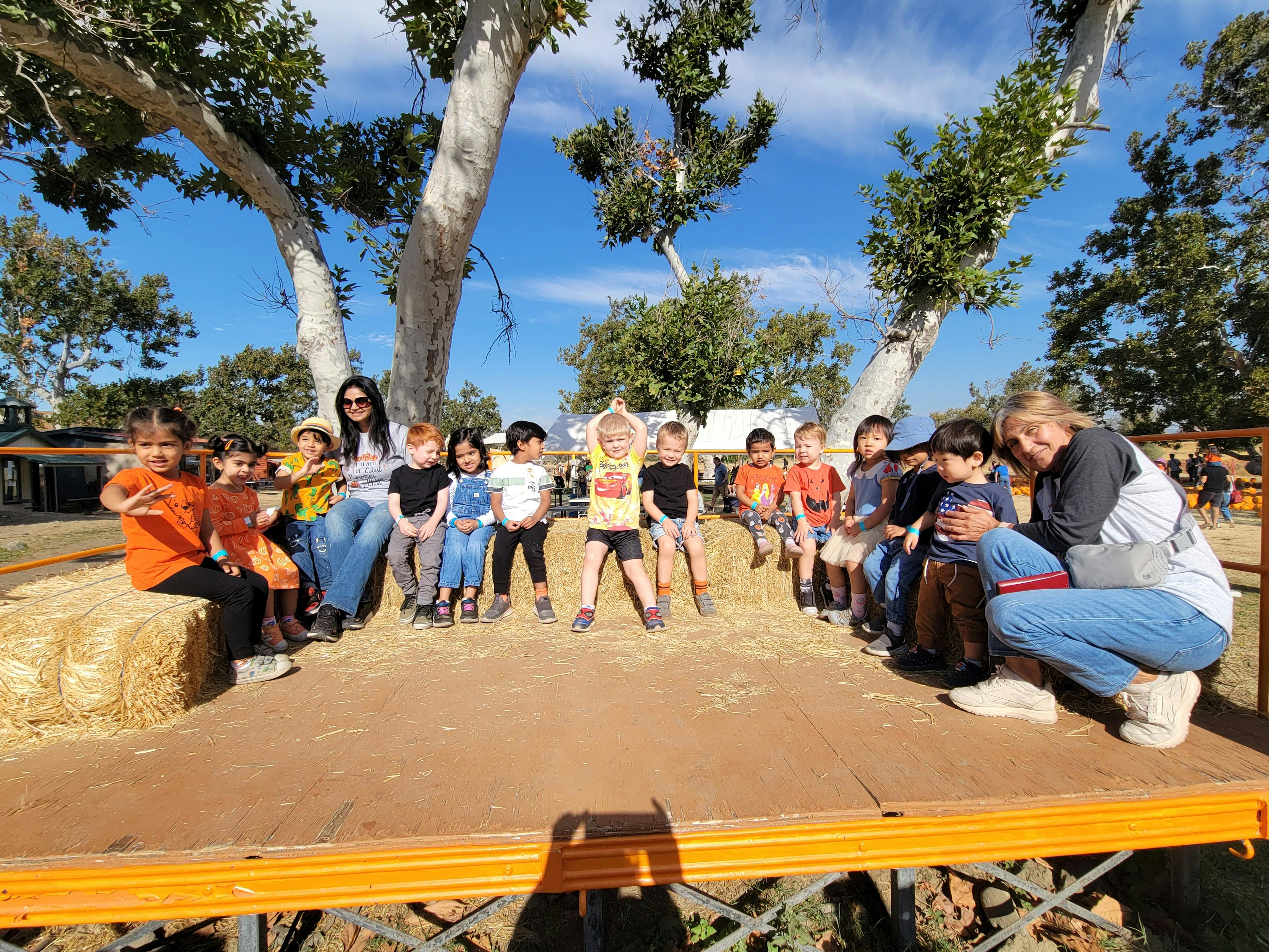 Two adults and multiple children sitting on a platform outdoors