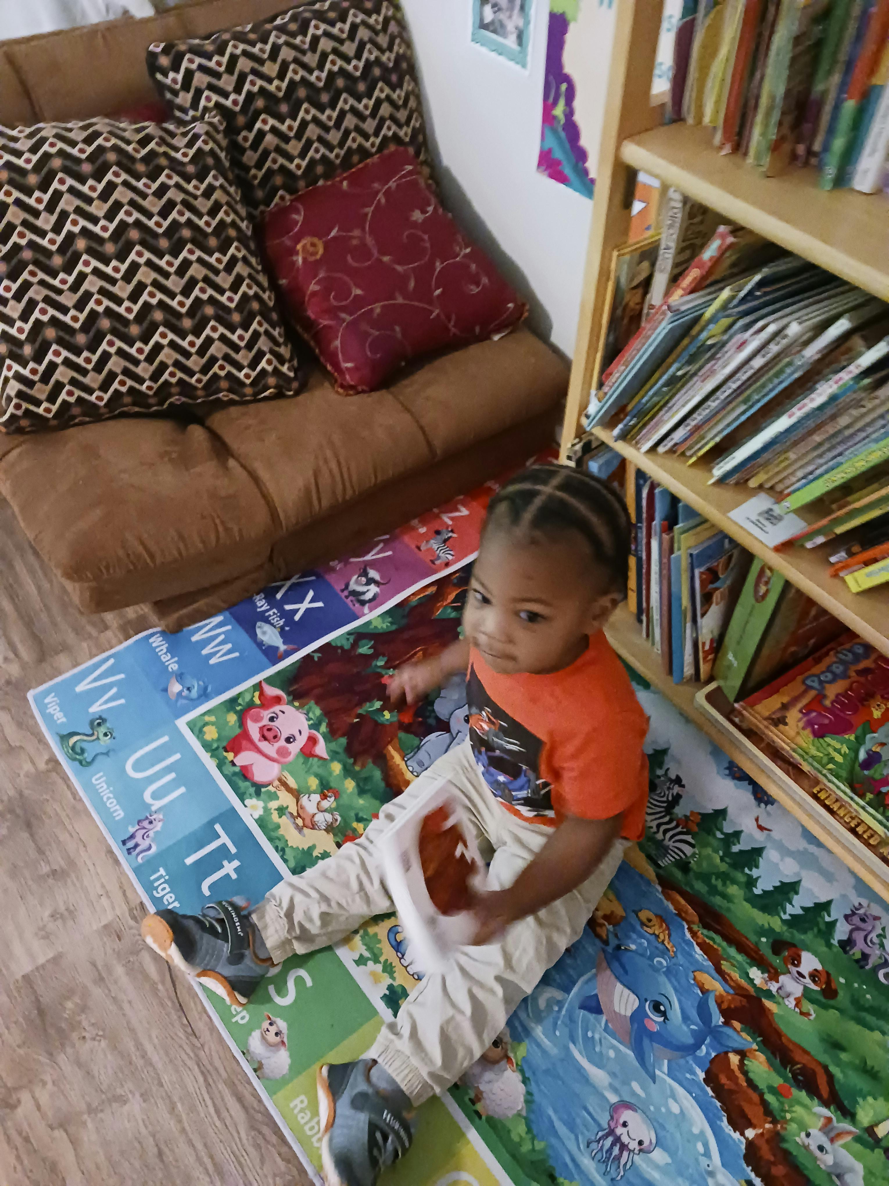 Child playing with a tray of food on an alphabet mat in a play area