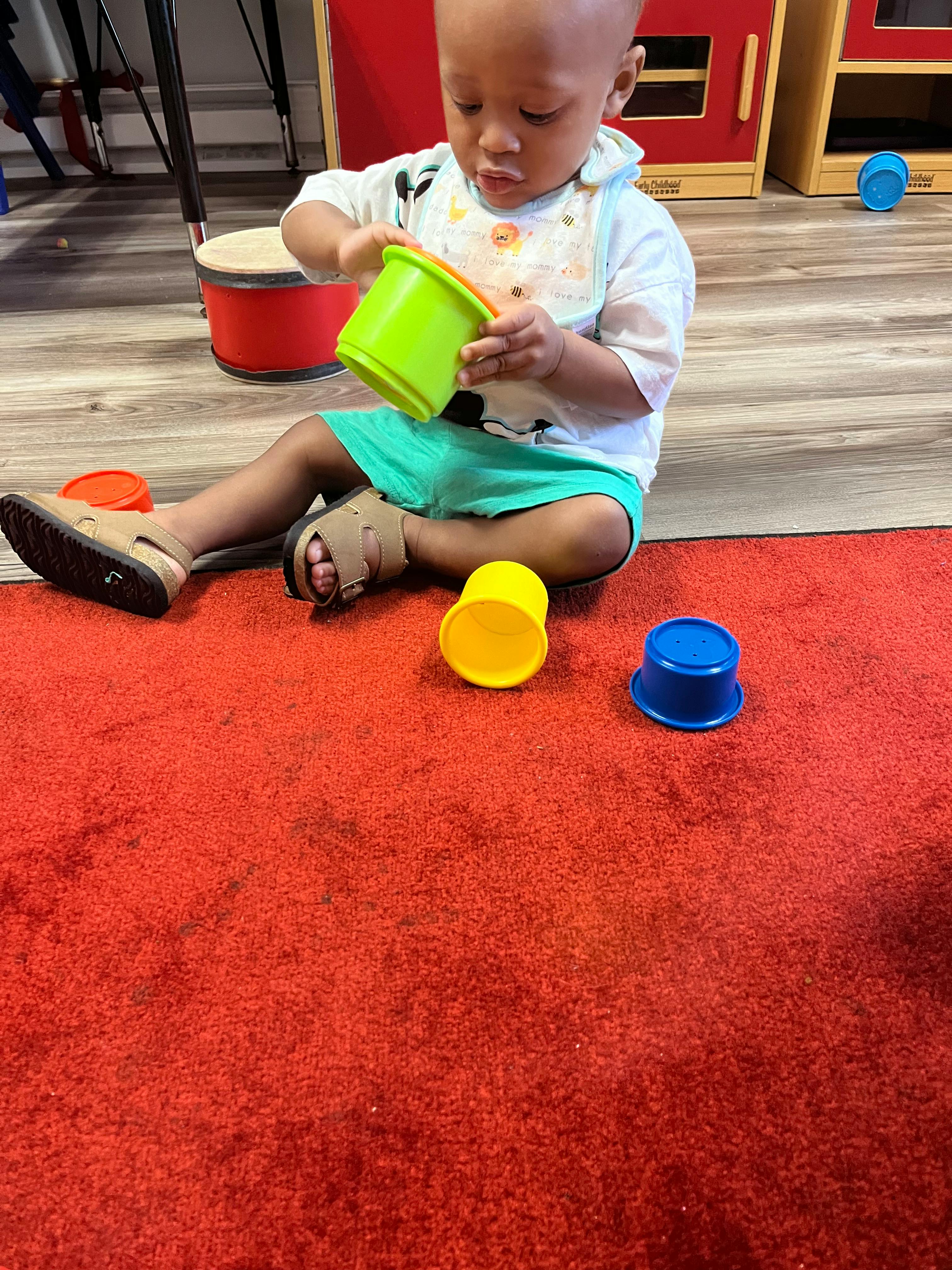Child sitting on floor playing with stacking cups