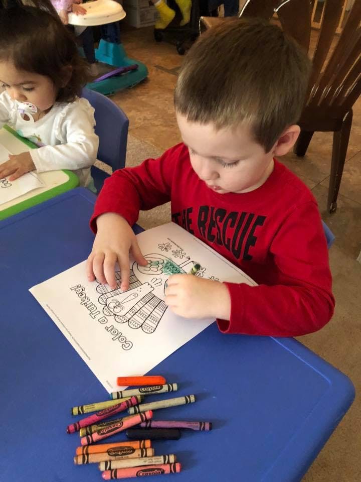 Child coloring a turkey picture at a table