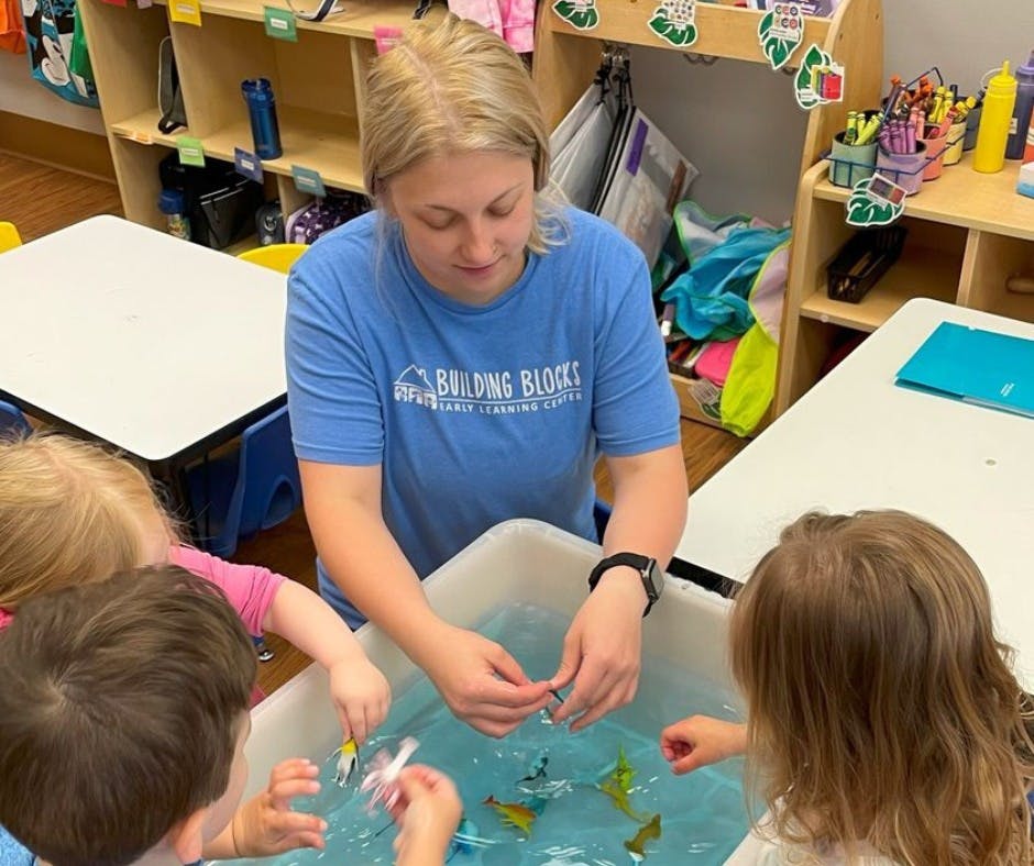 Adult and children playing with toys in a water table