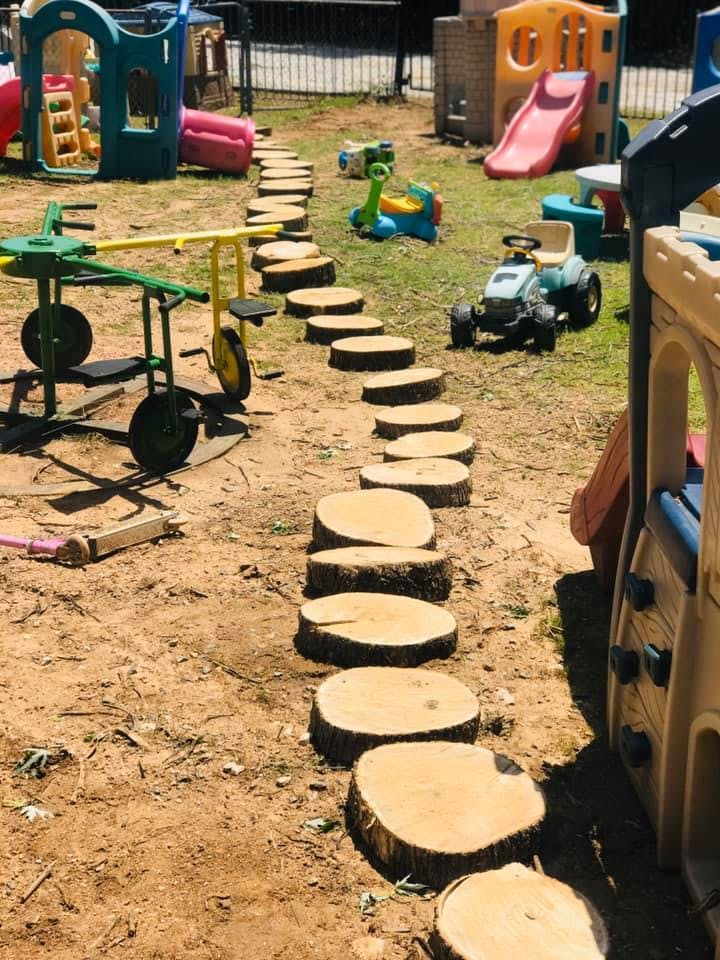 Wood stepping stones on a dirt path in a playground with toys