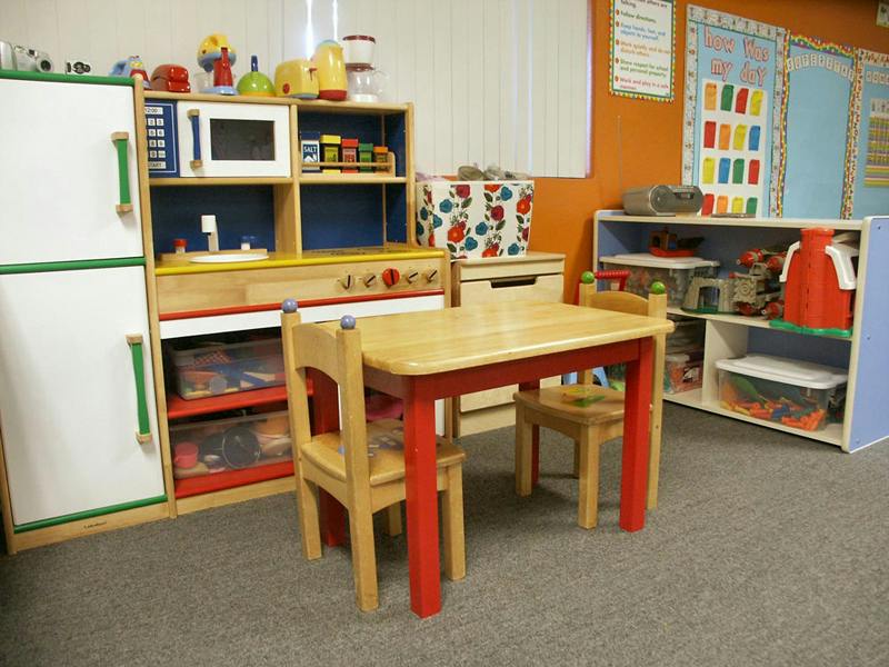Play kitchen set with a small table and chairs in a classroom