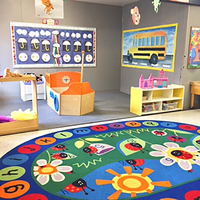 Playroom with a colorful rug, toy boat, and school bus artwork