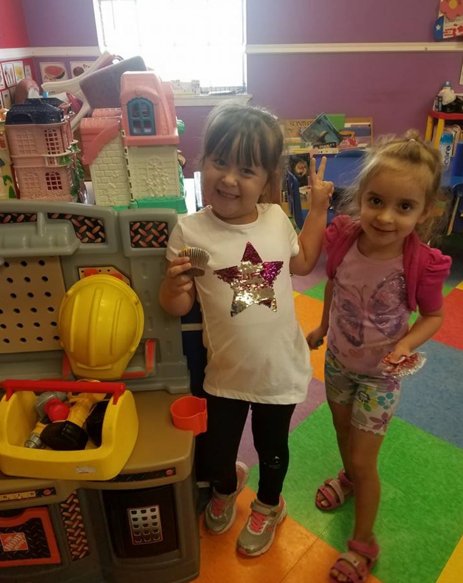 Two children standing next to a toy workbench