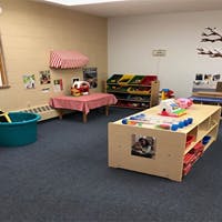 Empty classroom with tables, shelves, and a blue tub