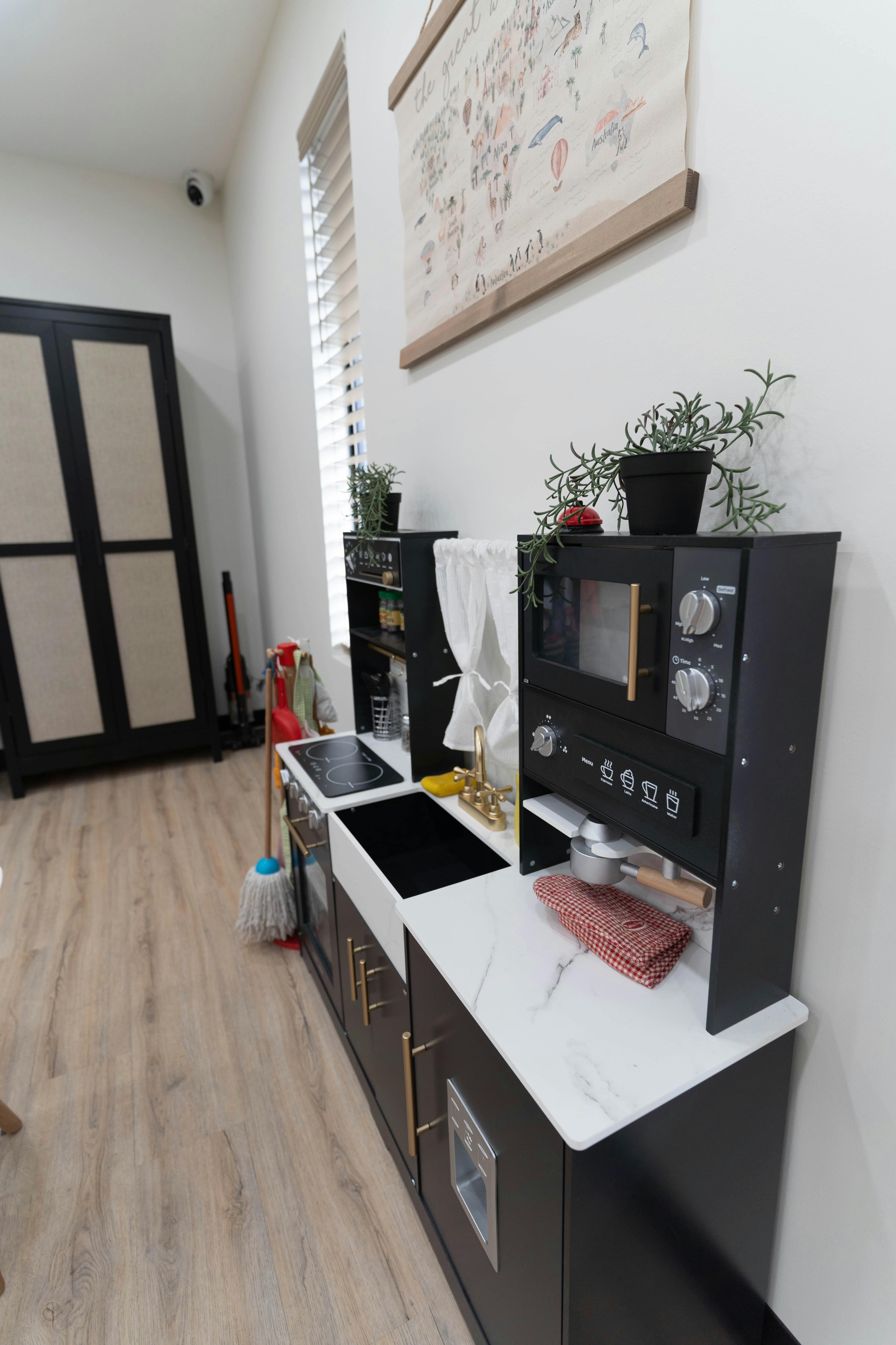Children's play kitchen with black cabinets and white countertops