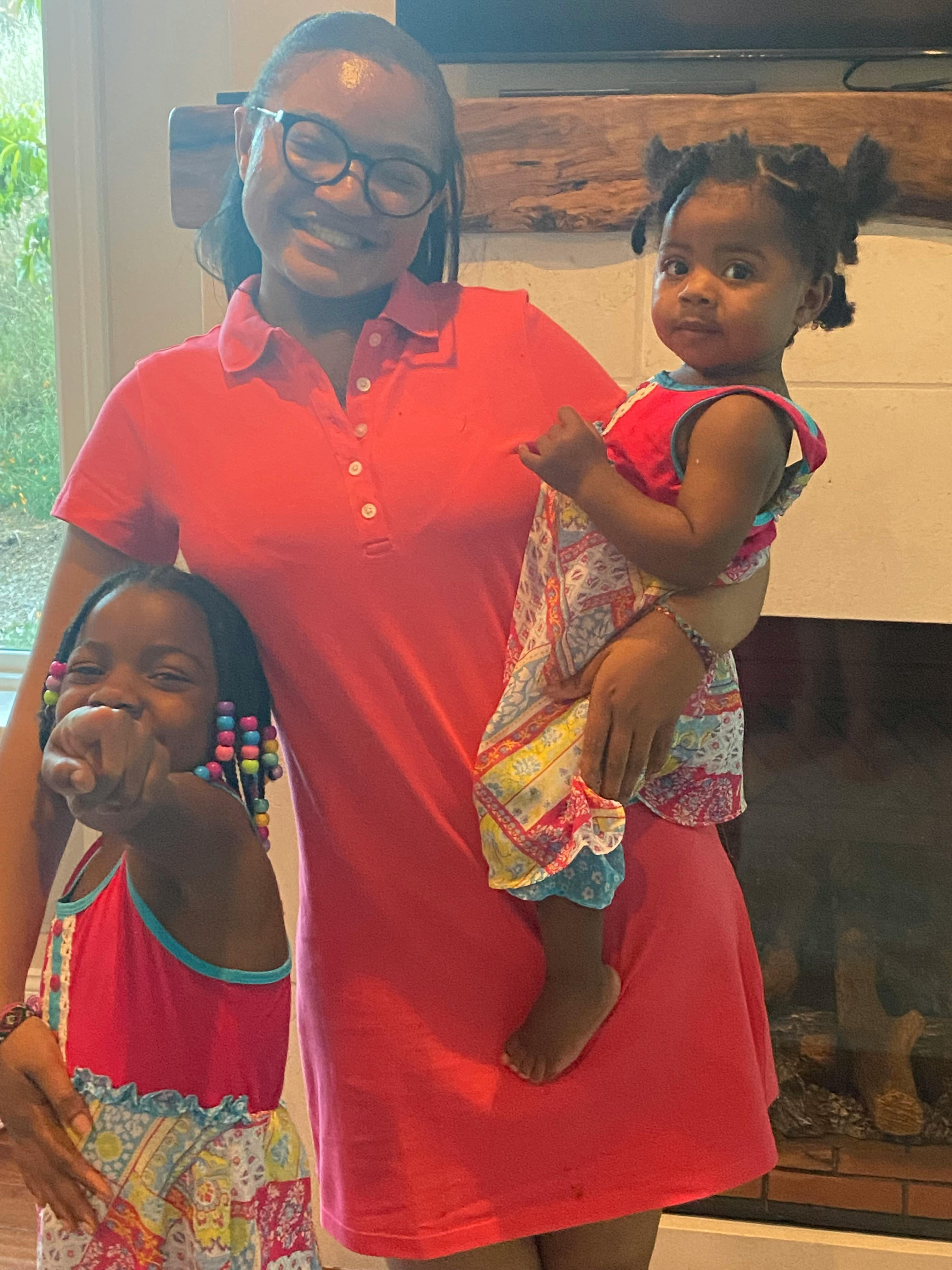 Person holding a child and standing next to another child