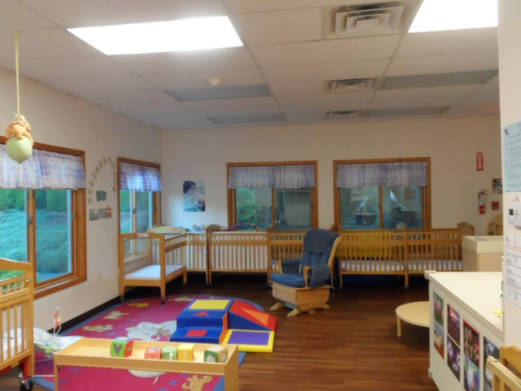 Nursery room with multiple cribs, a rocking chair, and play mats