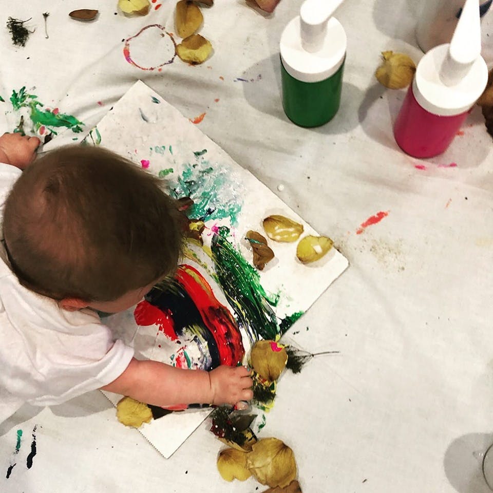 Child finger painting on a canvas with various colors