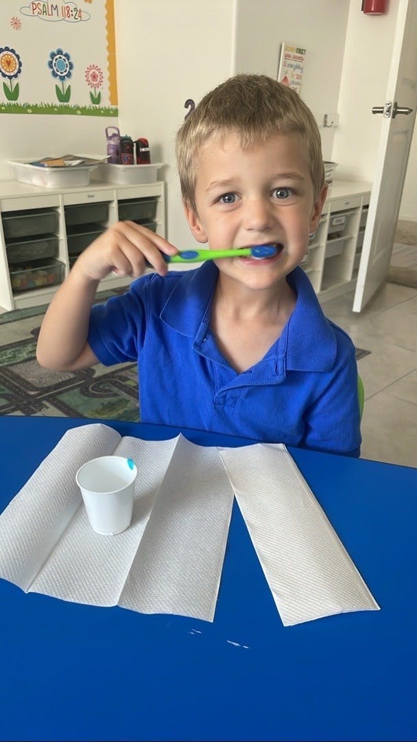 Child brushing teeth with a green toothbrush