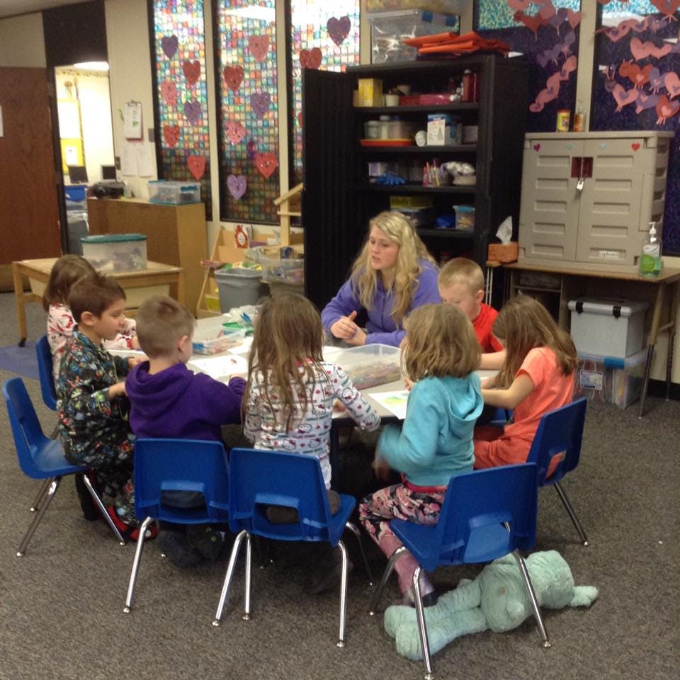 Adult and children sitting around a table in a classroom
