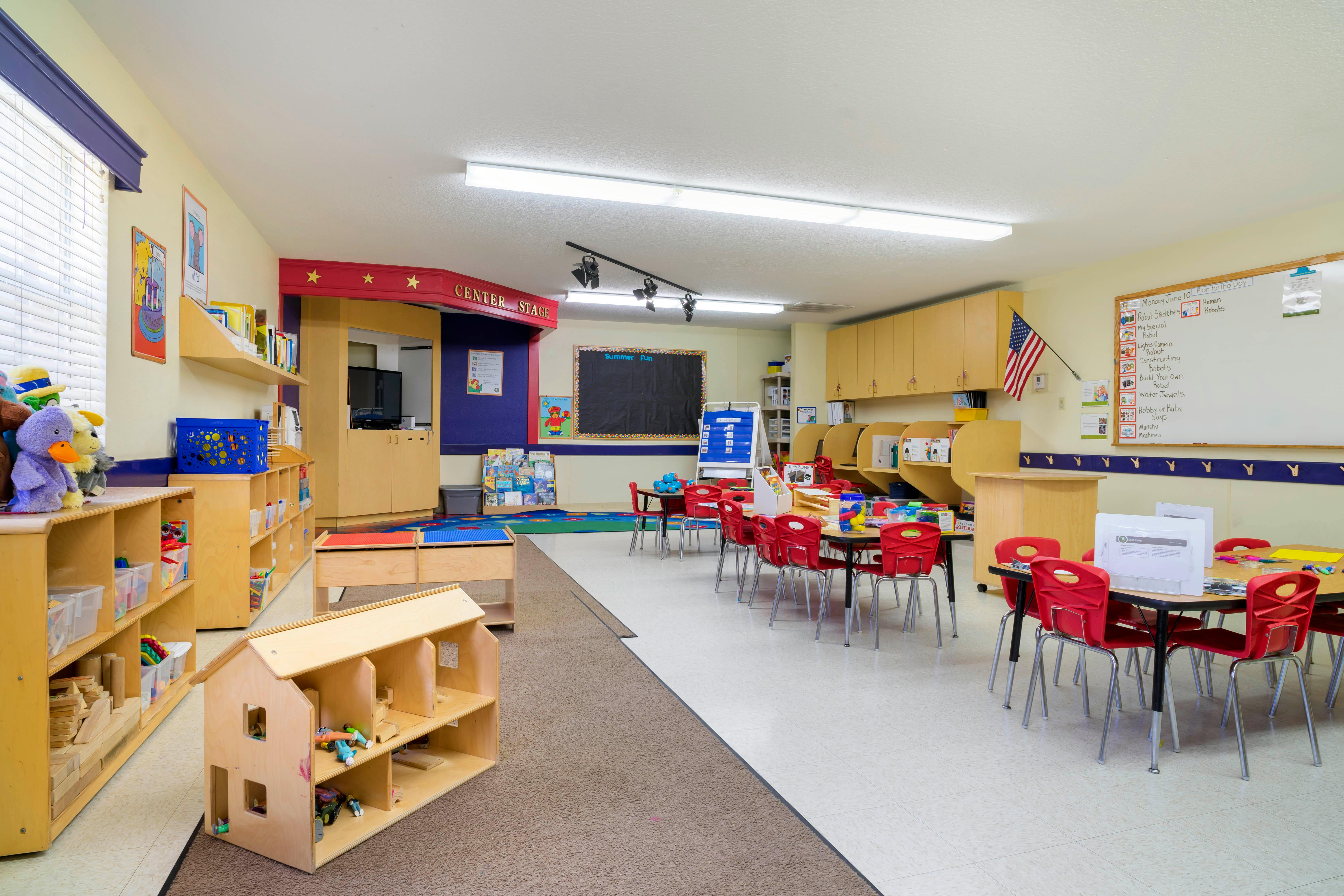 An empty children's classroom with small tables and chairs