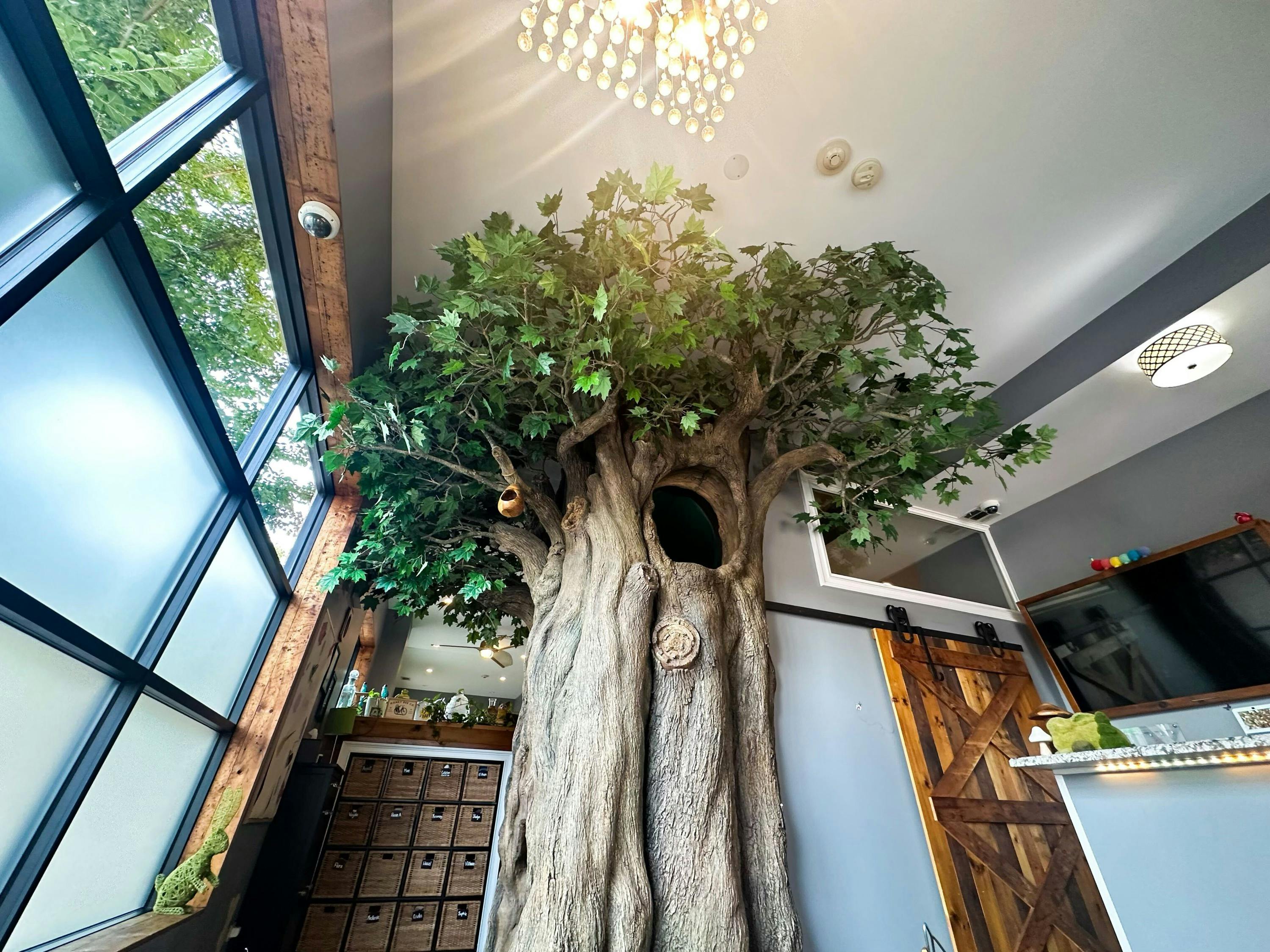Large artificial tree with green leaves and a hollow in a room