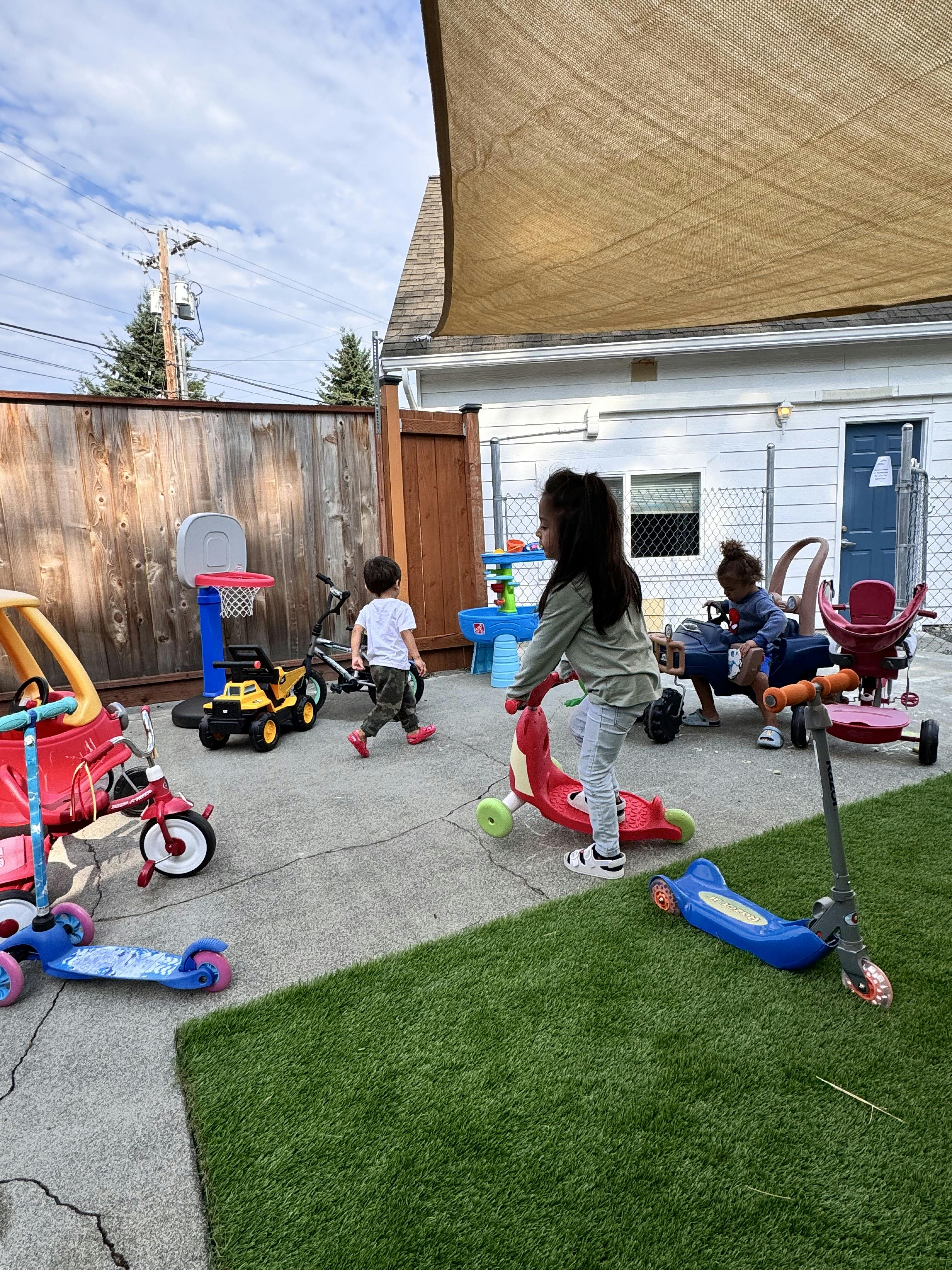 Children playing with scooters and toys in an outdoor area