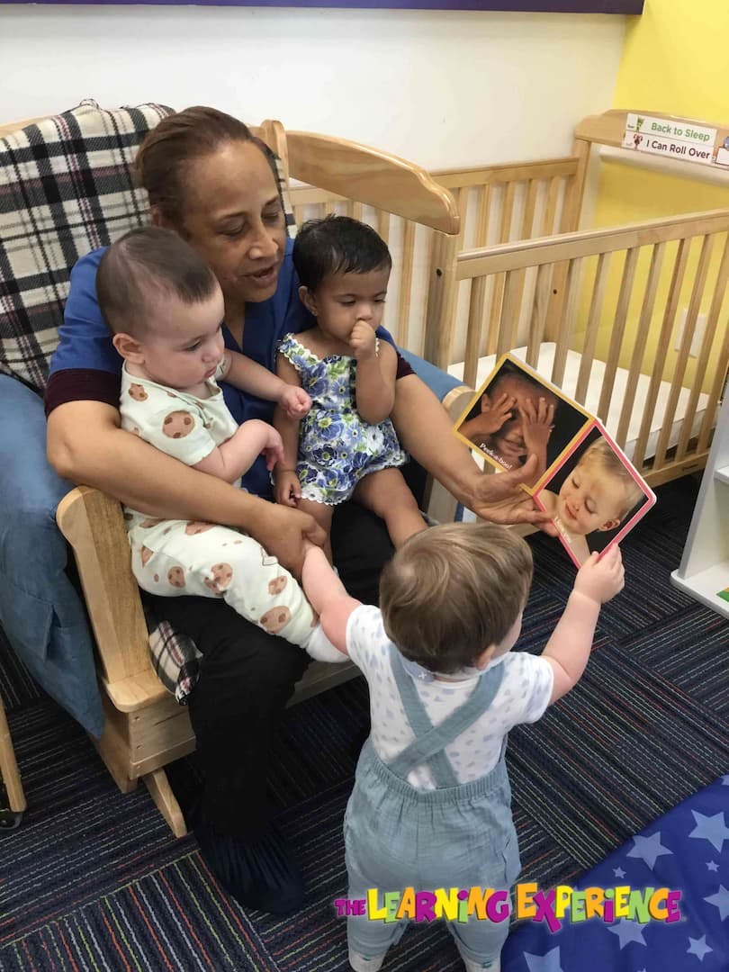 Person holding two children while another child holds a mirror