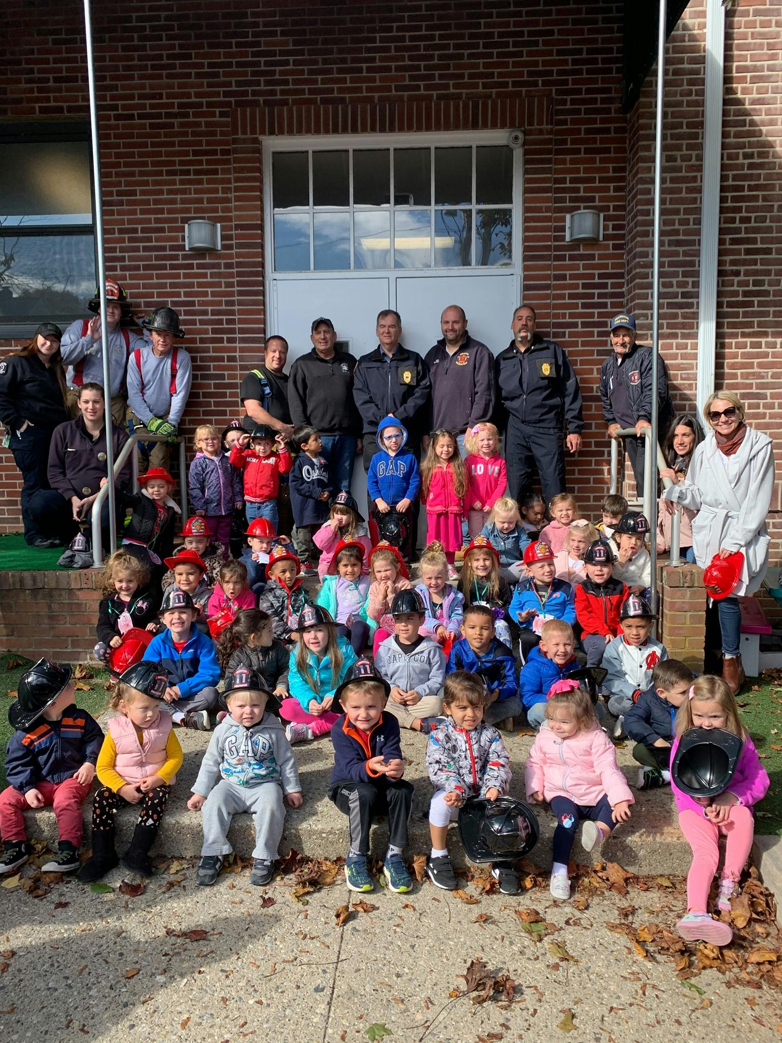 Group of adults and children posing on steps in front of a brick building