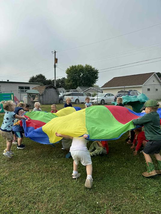 Group of children playing with a colorful parachute on a grassy field