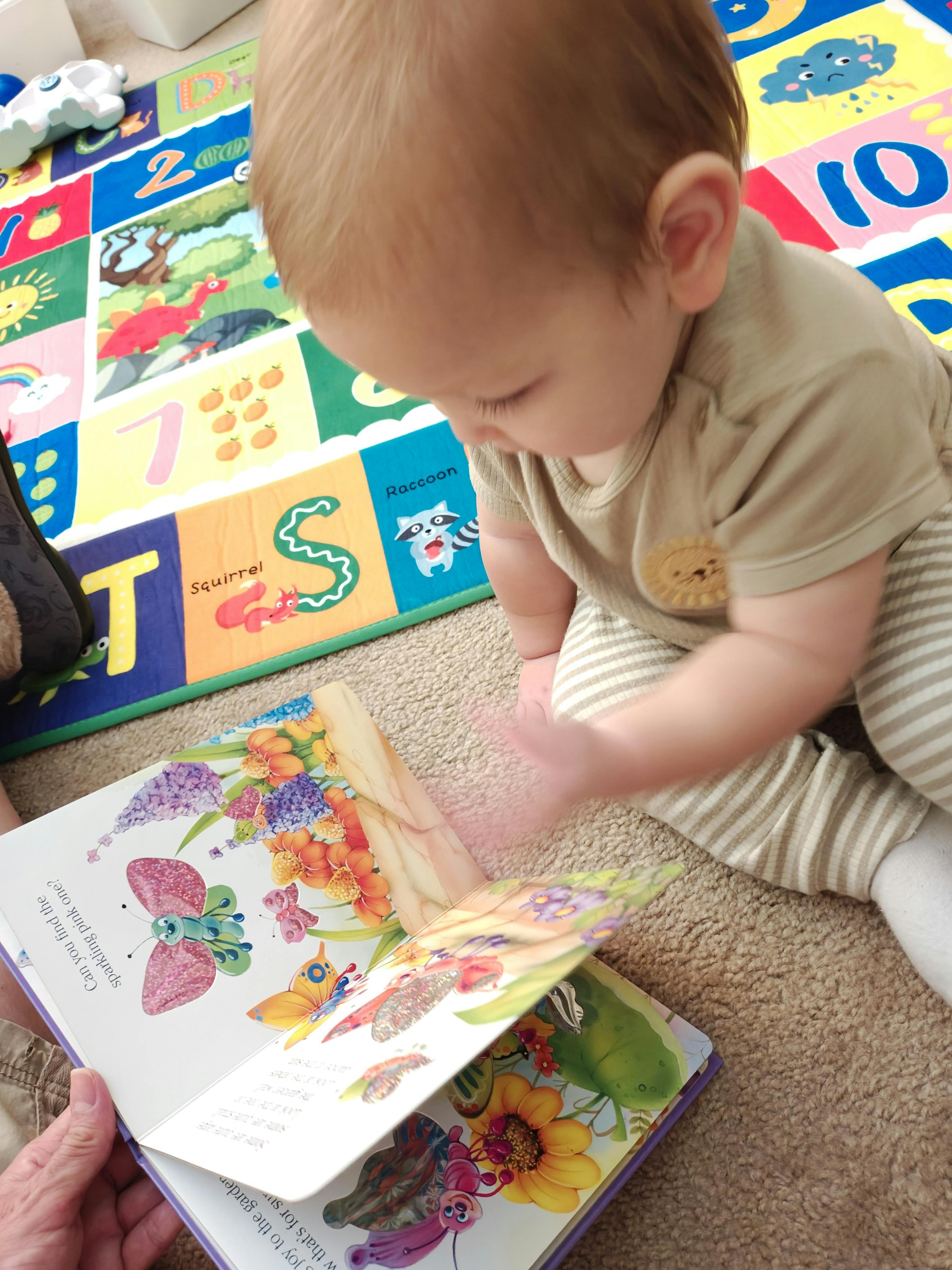 Child looking at an open book with colorful flower and butterfly illustrations