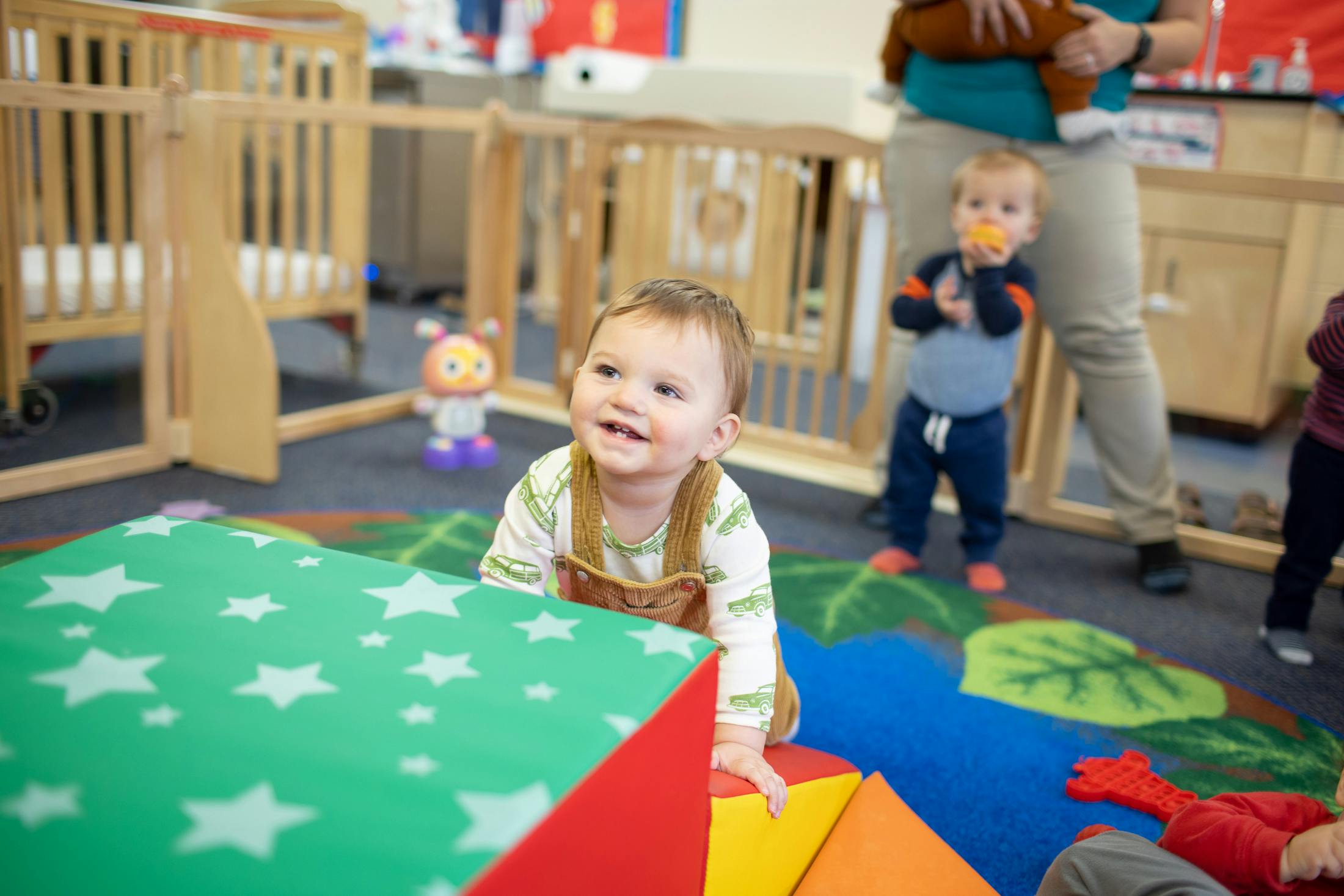 Child playing with soft blocks in a room with other children