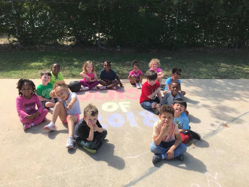Group of children sitting on pavement with chalk writing