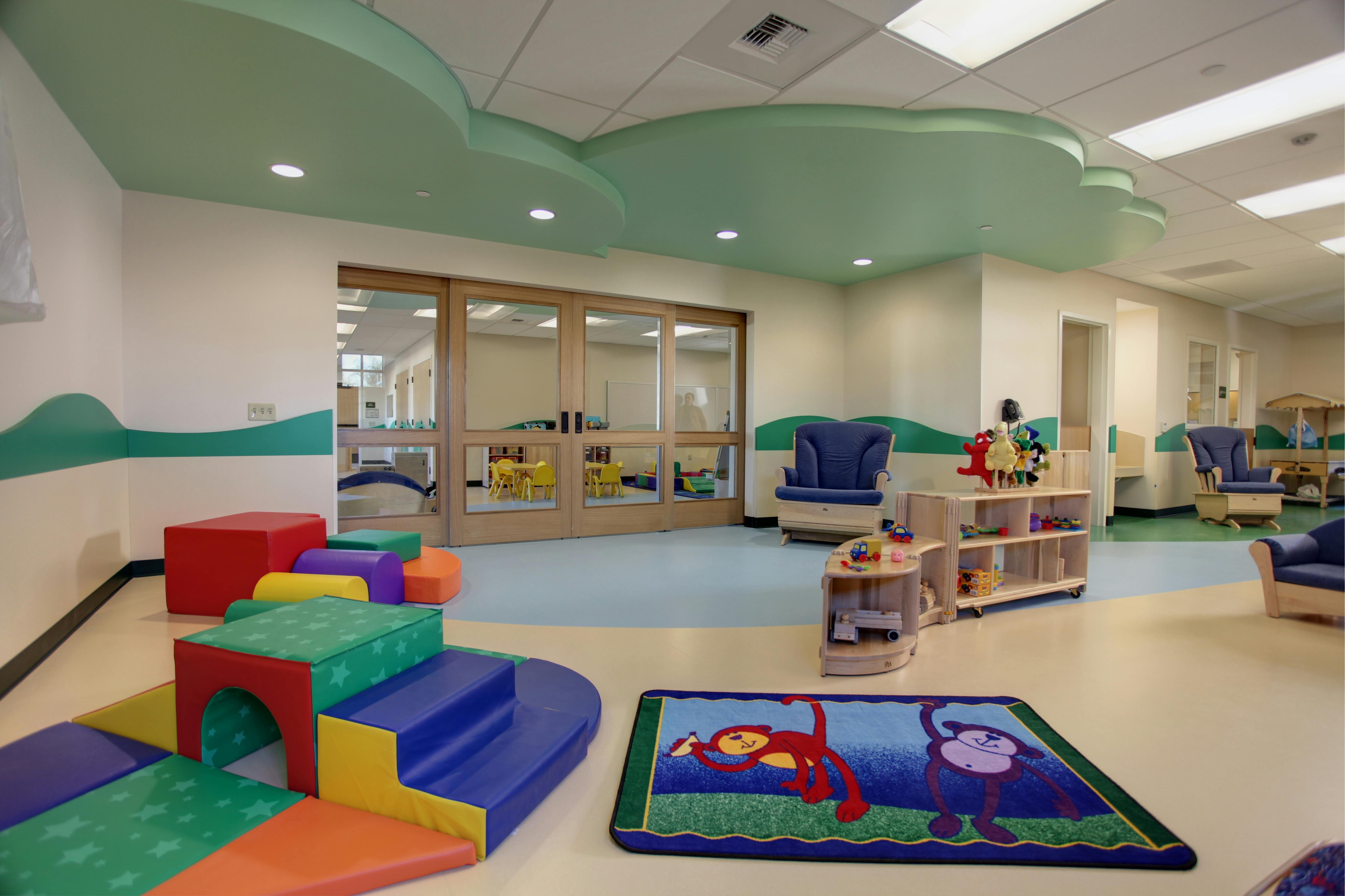 Colorful soft play equipment and small wooden shelves with toys in a children's room