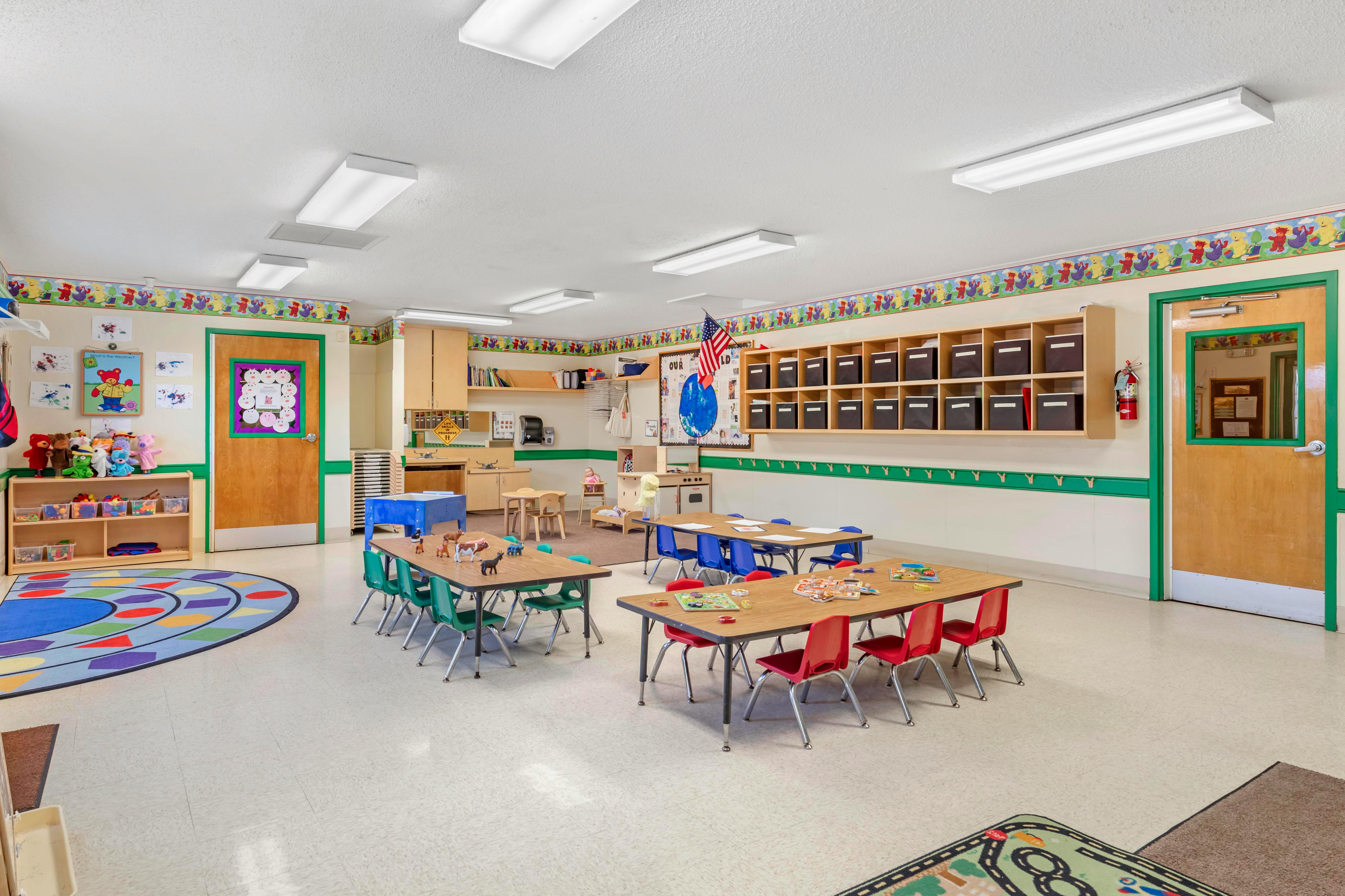 An empty bright children's classroom with small tables and chairs