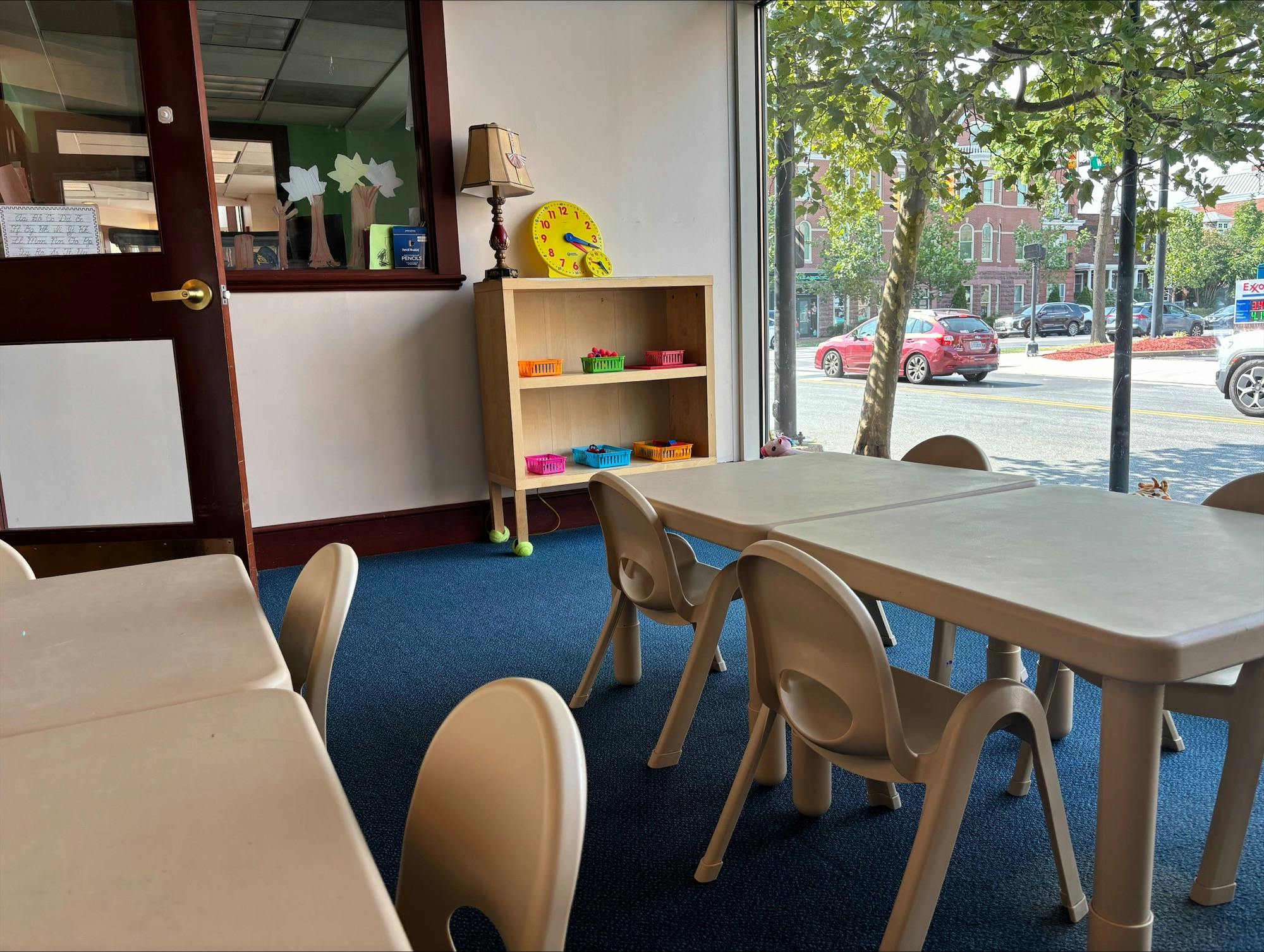 Classroom with small tables and chairs, bookshelf, and large window